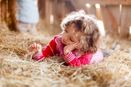 Beautiful little girl playing peacefully with hay wondering.の写真素材