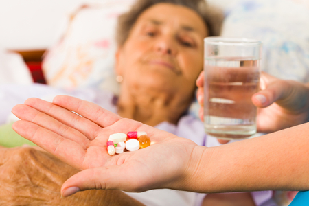 Homecare nurse helping elderly lady to take her daily medicine.の写真素材