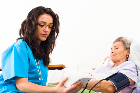 Nurse using digital blood pressure for senior patient.の写真素材