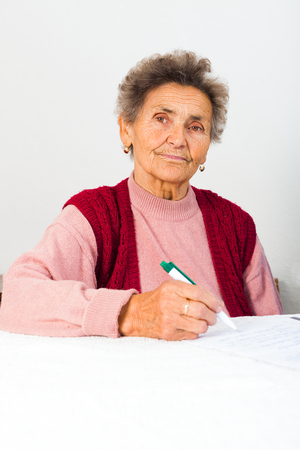 Elderly lady signing agreement contract bills.の写真素材
