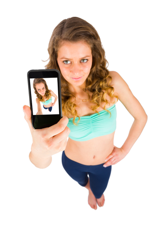 Cute girl takes selfies viewed from a different angle - studio photo.の写真素材