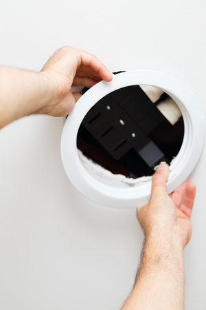 Electrician hands assembling ecological light in ceiling.の写真素材