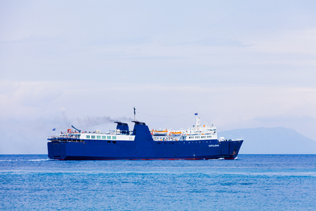 Big cargo ship and ferry boat in the blue waters of the ocean.の写真素材