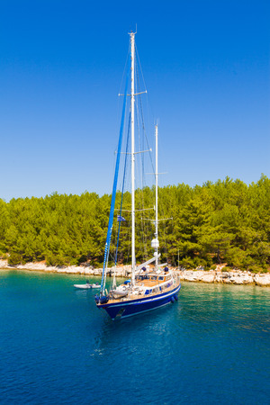 Shored yacht close to a mediterranean forest in the sea.の写真素材