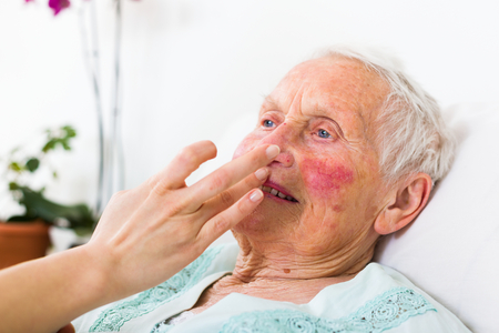 Helpful nurse caring for the senior woman in the nursing home.の写真素材