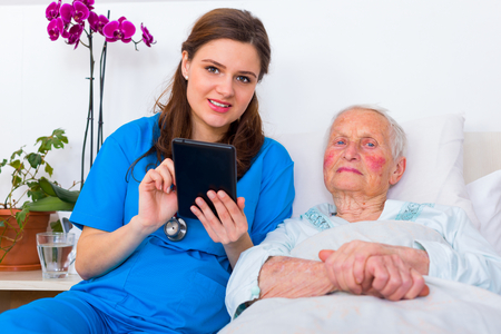 Caring doctor helping a senior patient to use a digital tablet.の写真素材