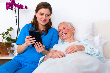 Caring doctor helping a senior patient to use a digital tablet.の写真素材