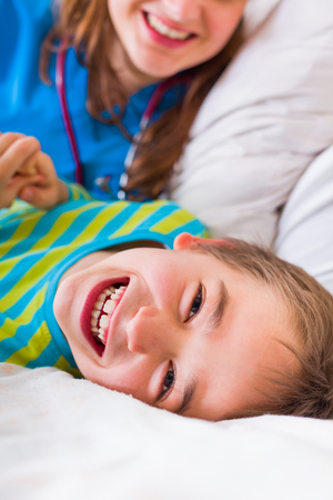 Happy sick little boy in bed in hospital getting well with professionalism and love.の写真素材