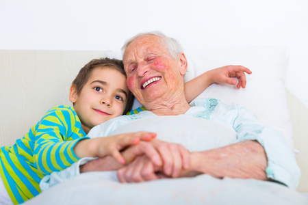 Sleepy grandmother preparing to sleep with her loving grandchild.の写真素材