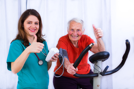 Elderly woman doing sport effort on a spinning bike having hear hart rate and blood pressure monitored.の写真素材