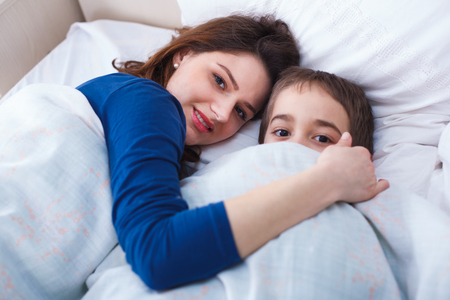 Mother and her little boy waking up at morning after a restful night.の写真素材