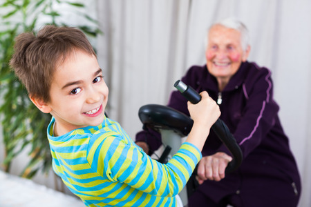 Grandmother training on stationary bike in the company of her grandson.の写真素材