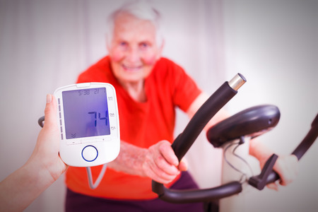 Elderly woman training, making effort, having hear heart condition, rate and blood pressure monitored by geriatric doctor.の写真素材