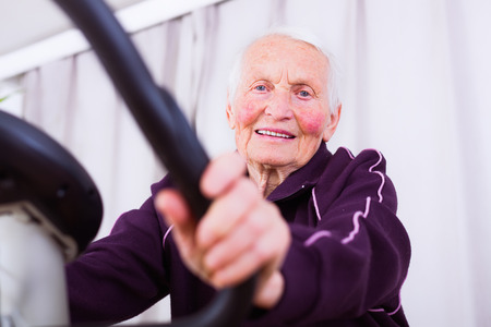 Senior woman on stationary bike indoors in a nursing home.の写真素材