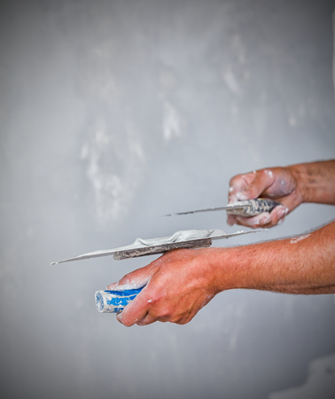 Professional construction worker applying skim coating material to the freshly made plasterboard...