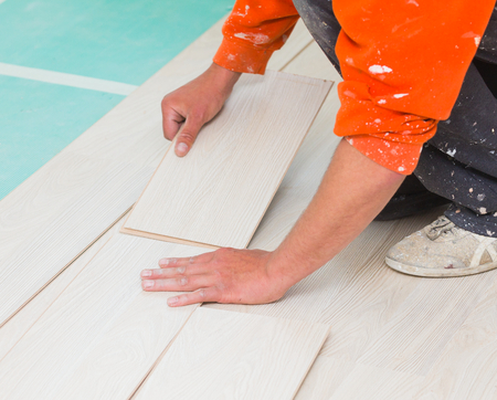 Handyman laying down laminate flooring boards while renovating a house.の写真素材