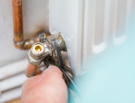 Handyman mounting copper conduit on home radiator.