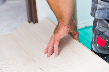 Handyman laying down laminate flooring boards while renovating a house.の写真素材