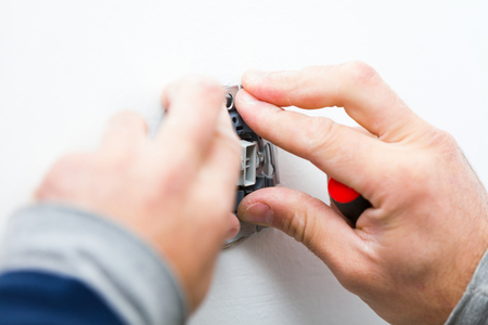 Electrician installing light on a wall using special tools.の写真素材