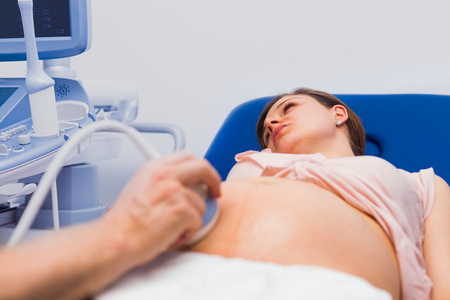 Gynaecologist doctor examining pregnant female patient with ultrasound machine.の写真素材