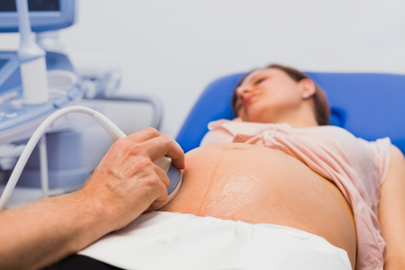Pregnant young woman at gynaecologist having her baby examined with ultraound device.の写真素材