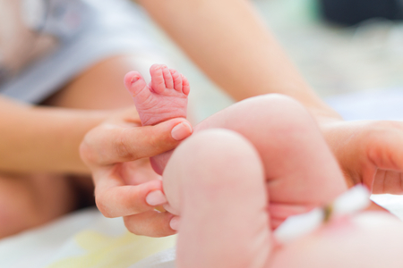 Mother holding her baby's tiny feet in bed at maternity hospital.の写真素材