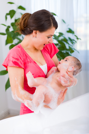 Young mother taking her child out of the bathtub playfully.の写真素材