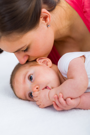 Young mother consoling her beautiful child with a kiss.の写真素材