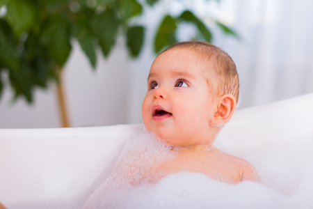 Beautiful baby taking a bubble bath with a lot of foam.の写真素材