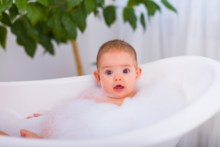 Beautiful baby taking a bubble bath with a lot of foam.の写真素材