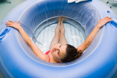 Pregnant woman sitting in water pool in hospital between labour cramps.の写真素材