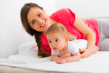 Beautiful young mother in bed with her child in the bedroom.の写真素材