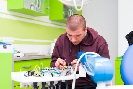 Medical equipment engeneer fixing a dental chair in the office of the dentist.