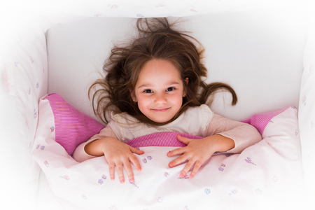Little girl smiling in bed before getting up. She had a good night.の写真素材