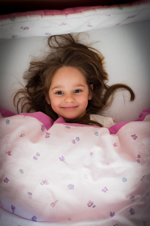 Little girl smiling in bed at night, before sleeping.の写真素材