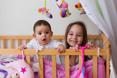 Two sisters in bed at night / in the morning spendig playful time together.の写真素材