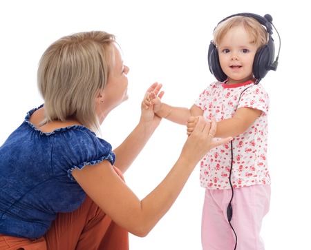 Little girl dancing with headphones holding her mothers hands - isolatedの写真素材