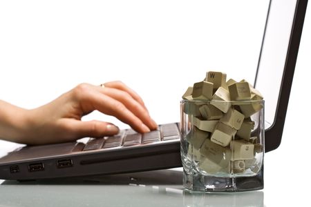 A shot of inspiration concept - glass with computer keyboard keys and woman hand typing on laptop