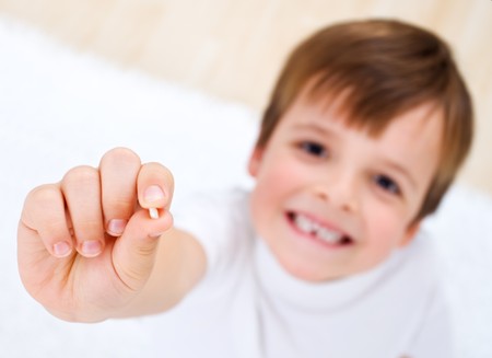 Little boy showing his first lost milk-tooth in his hand - closeupの写真素材
