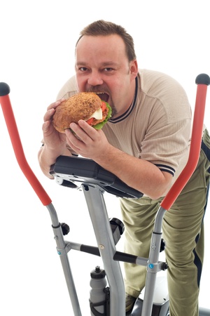 Man eating huge hamburger while resting on a trainer device - isolatedの写真素材