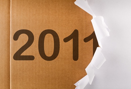 Torn wrapping paper revealing 2011 written on brown cardboard layer - new year concept