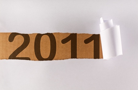 Torn wrapping paper revealing a strip of brown cardboard with 2011 written over - new year conceptの写真素材