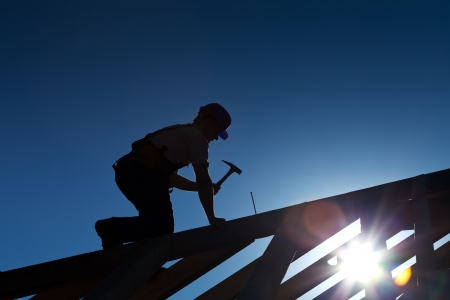 Builder or carpenter working on the roof - silhouette with strong back lightの写真素材