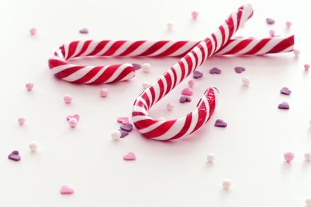 Christmas candy sticks and scattered sweets on white surfaceの写真素材