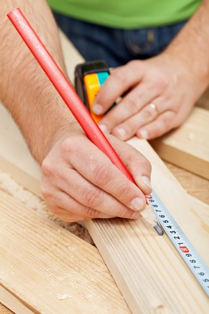 Carpenter or joiner measuring wood and marking with pencil - closeupの写真素材