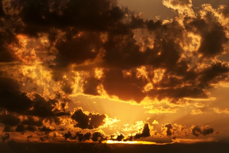 Dramatic sunset shining through dissolving cloudsの写真素材