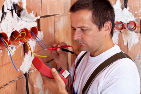 Electrician working - measuring the wiring in a new houseの写真素材