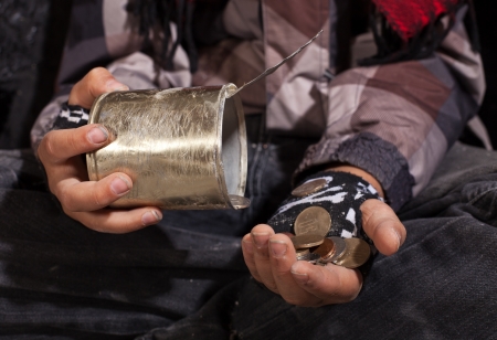 Poor beggar child counting coins - closeup on dirty hands holding tin canの写真素材