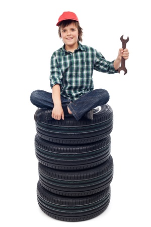 Young mechanic with car tires and spanner sitting - isolatedの写真素材
