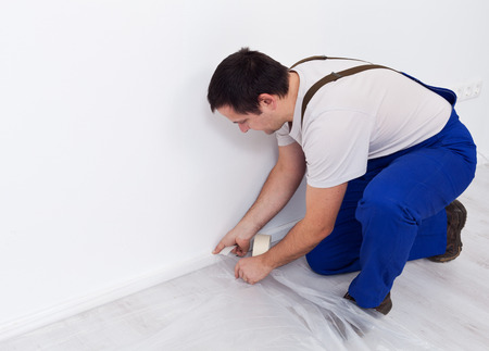 Painter worker preparing the room - laying protection film layer, with copy spaceの写真素材